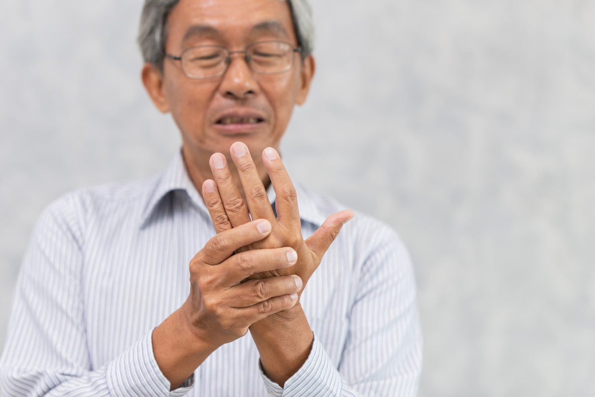 older man with arthritis holding up his hand.