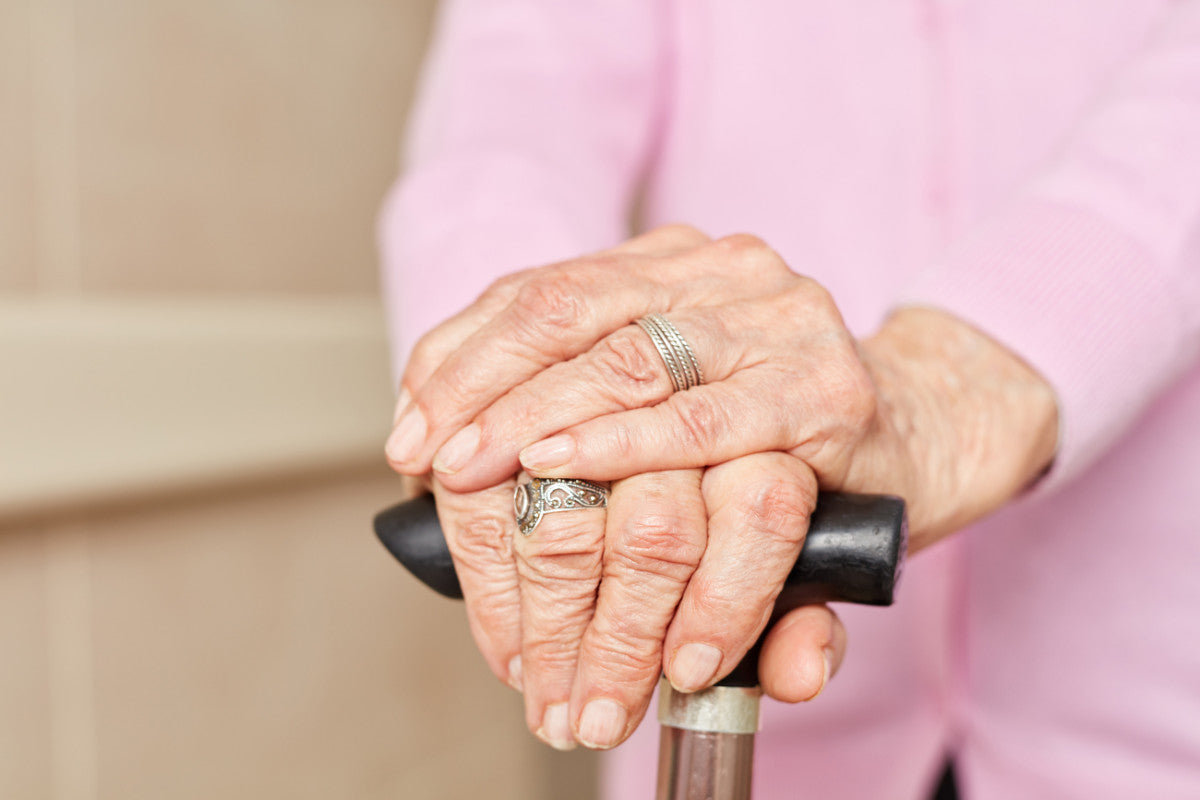 close-up of senior woman's hands crossed over her cane