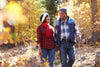 senior couple bundled up, taking a walk through the woods during autumn