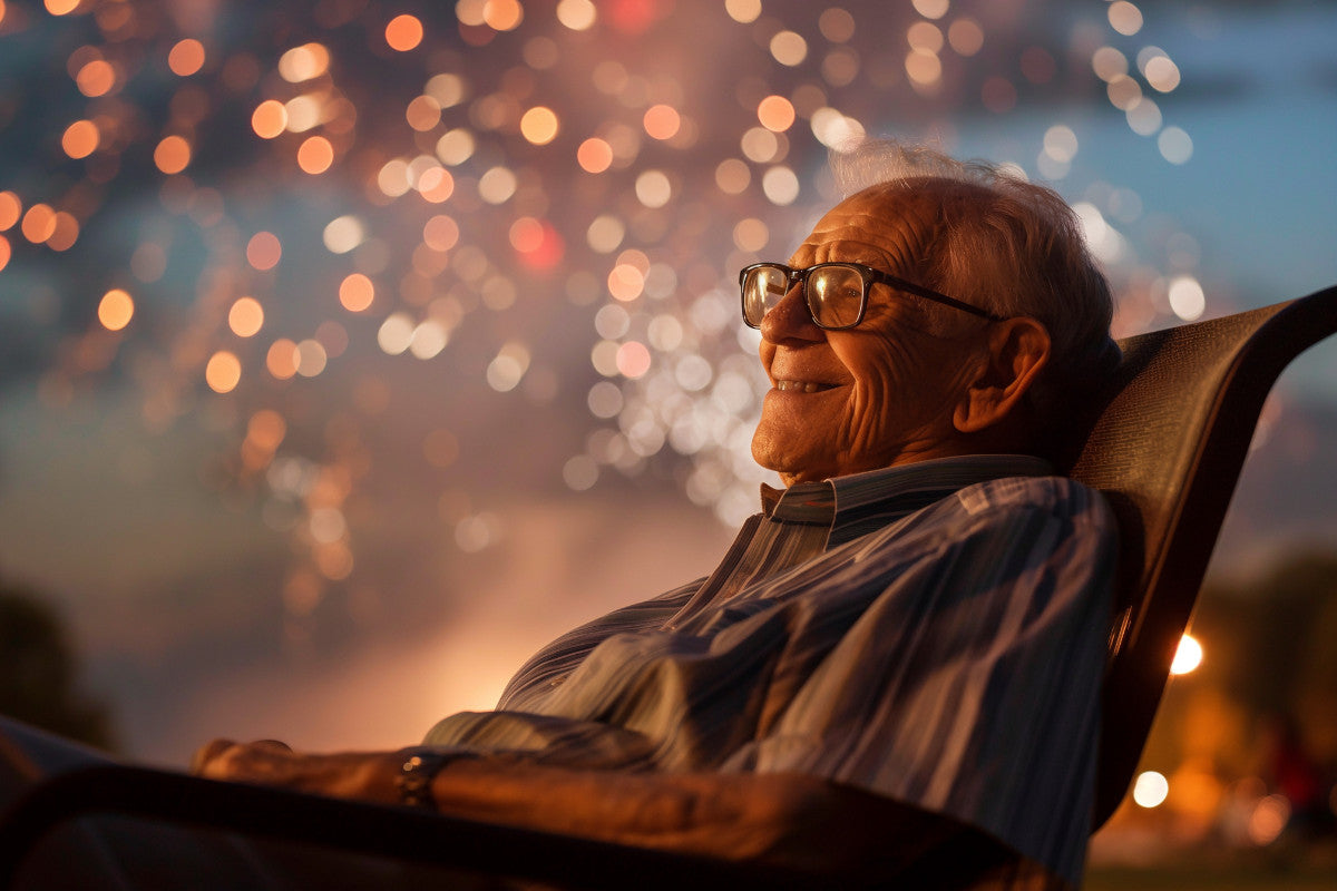 Senior man sitting in a chair outside watching the fireworks.