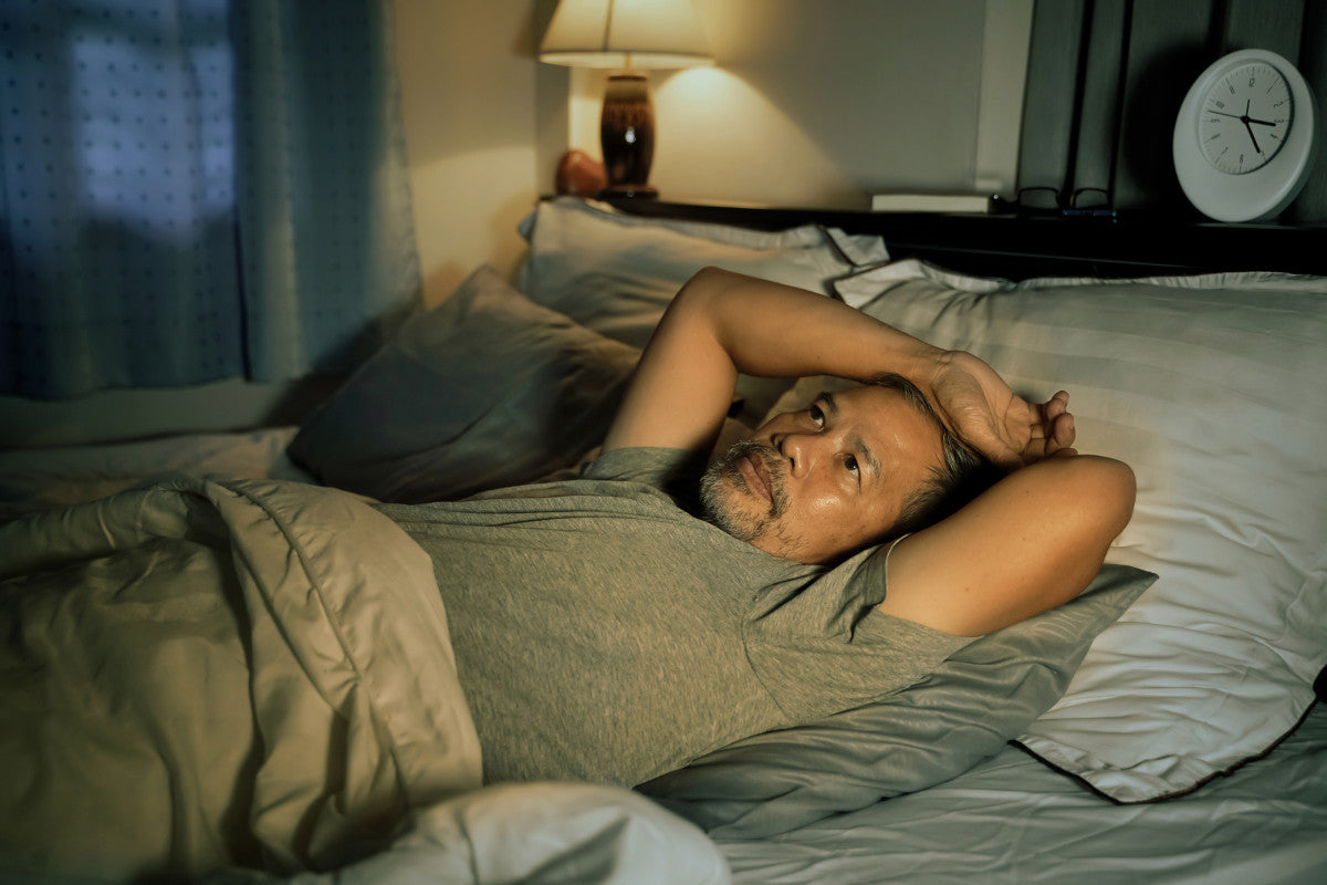 older man having trouble sleeping, wide-awake in bed.