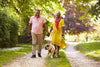 older couple laughing and smiling as they take a walk on a nature trail with their dog