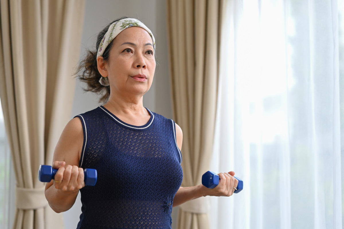 Senior woman lifting small weights in her living room.
