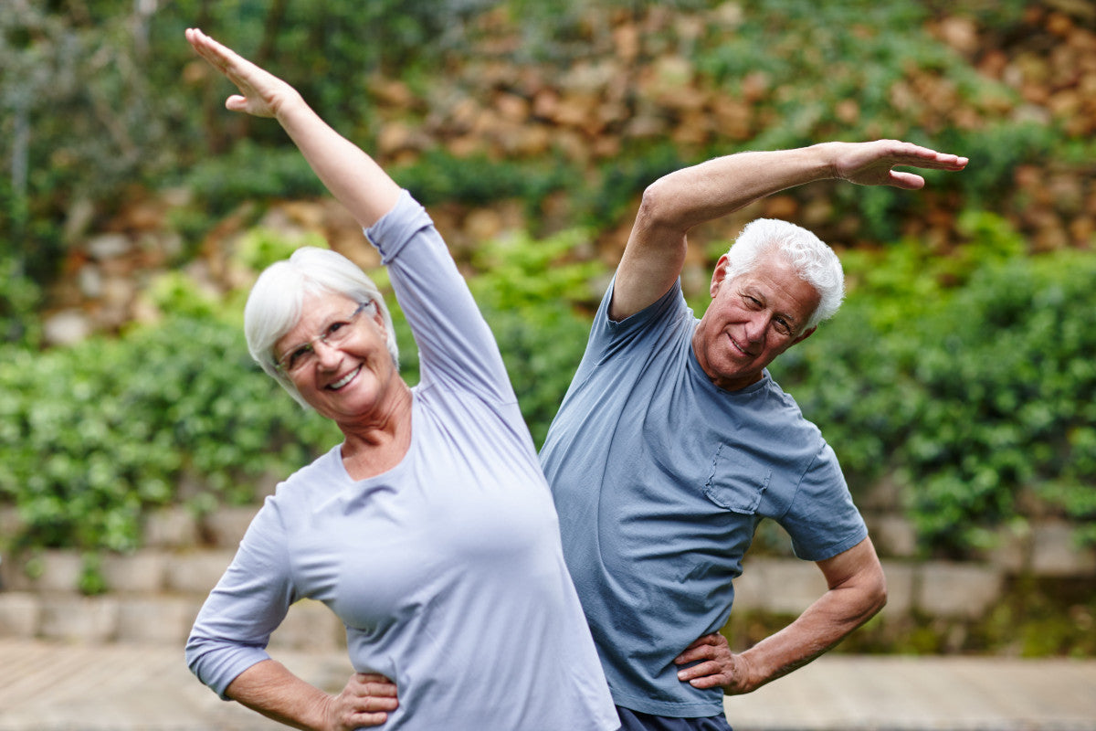 Senior couple doing the side stretch outside.