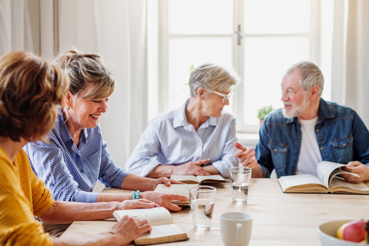 4 seniors reading books together at a table