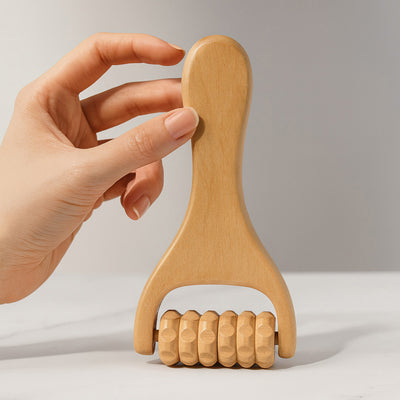 Hand holding the wooden massager upright, showing its ridged wooden roller