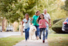family with dog running and walking down the sidewalk