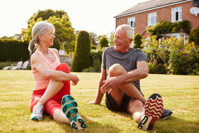 senior couple stretching on the grass outside their house together