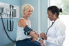 female doctor checking blood pressure of an older female