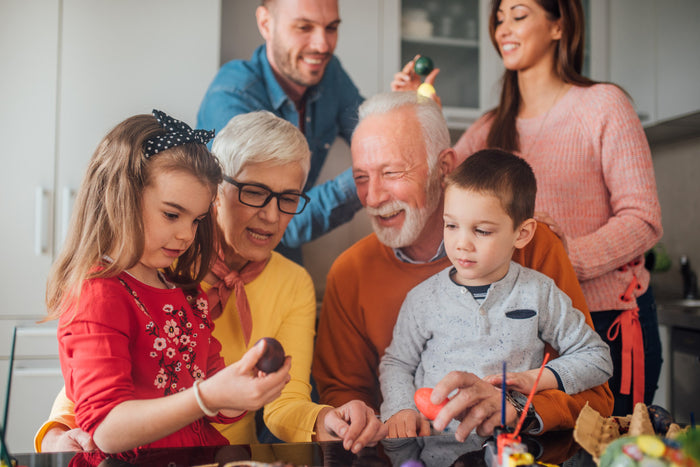 grandparents, parents, and two kids hanging out in the kitchen painting Easter eggs
