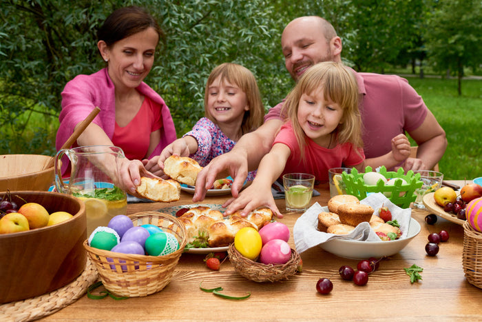 family of 4 sitting outside at a table, enjoying baked goods