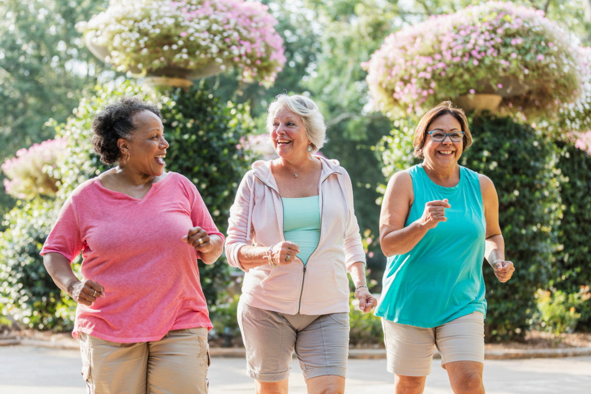 group of three older women enjoying each other's company outside while they fast-walk together