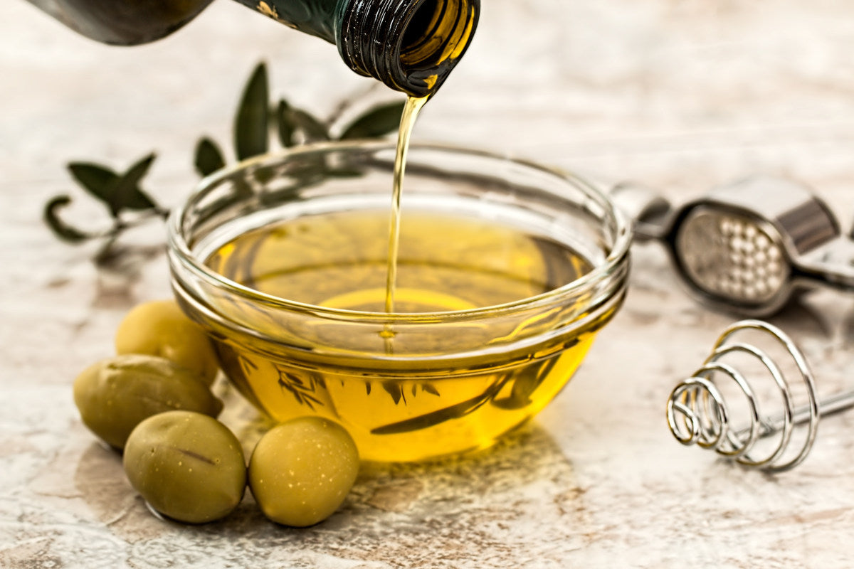 pouring olive oil into small glass bowl