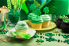 St. Patrick's Day table set up with St. Patrick's Day decorations and green-frosted vanilla cupcakes