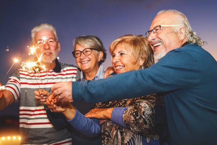group of 4 seniors holding sparklers, celebrating July 4th