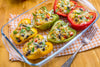 6 stuffed bell peppers in a glass pan on a wooden table.