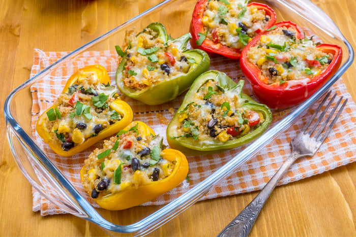 6 stuffed bell peppers in a glass pan on a wooden table.