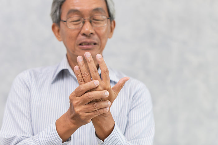 older man with arthritis holding up his hand.