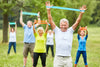 group of seniors using resistance bands while exercising outside.