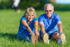 older couple smiling, sitting on the grass outside and stretching