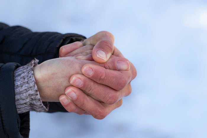 background of snow. foreground with senior holding their very, very cold hands together.