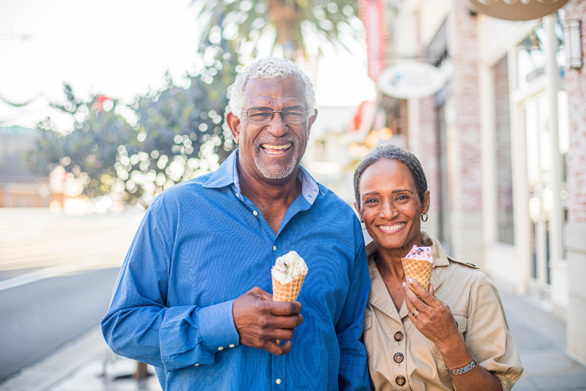 happy senior couple smiling at the camera and holding up ice cream cones
