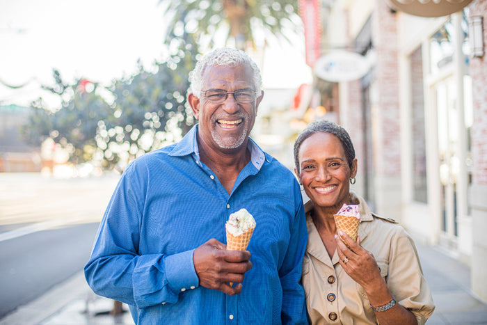 happy senior couple smiling at the camera and holding up ice cream cones