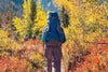 senior man with large backpack hiking on a trail in the fall.