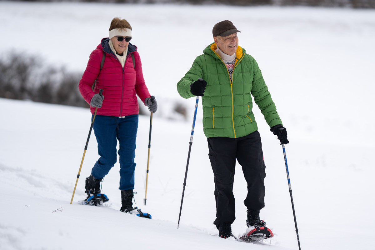 senior couple smiling and having a good time while they snowshoe.