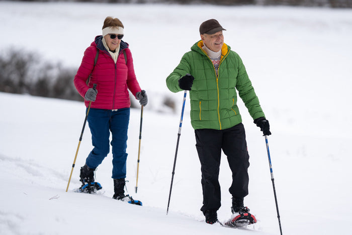 senior couple smiling and having a good time while they snowshoe.