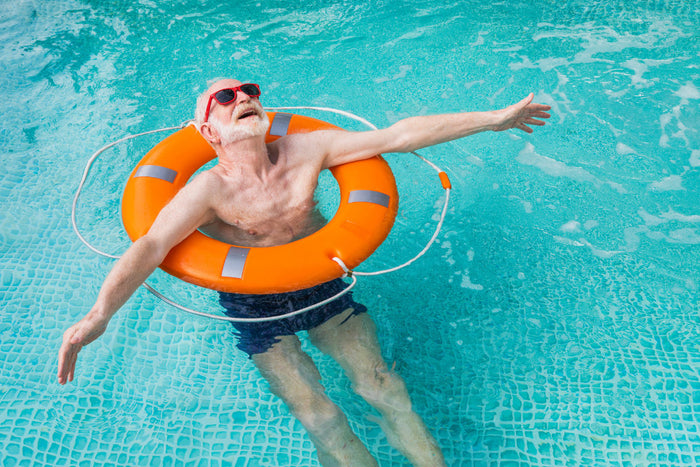 Senior man floating in an orange raft in a pool.