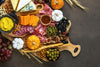 charcuterie board with various meats, cheeses, pickles, and pumpkins