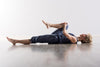 woman lying on her back with one leg fully extended and one leg bent- practicing the hamstring stretch.