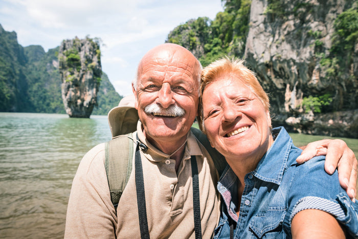 happy senior couple taking a selfie as they explore a nearby beach.
