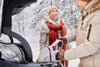 senior couple packing the car in the winter, snow is on the ground and they're wearing heavy coats.