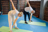 Senior couple stretching on green yoga mats inside.
