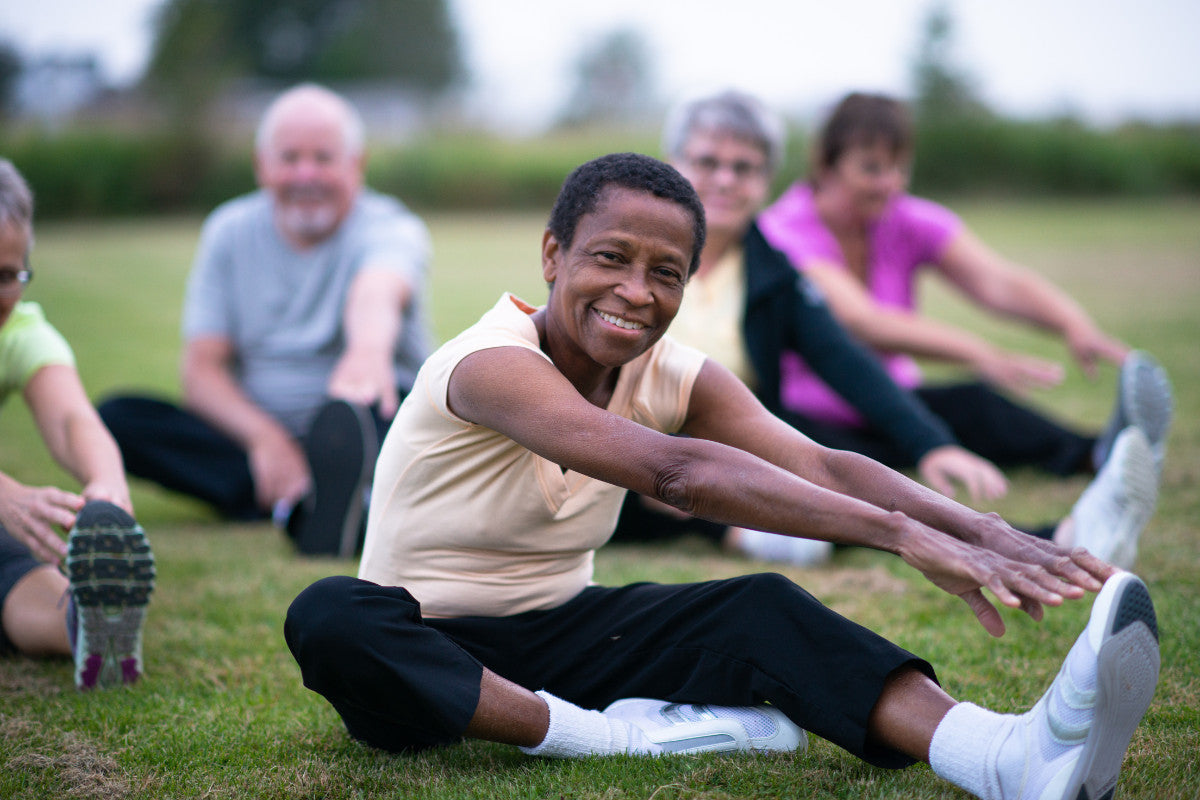 group of older people stretching on the grass outside